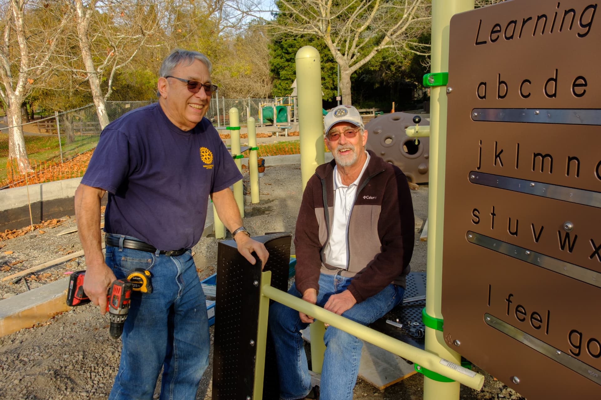 Two Rotary volunteers building a playground learning panel